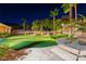 The well-lit putting green is surrounded by lush landscaping and complemented by a cozy lounge area at 2064 Poetry Ave, Henderson, NV 89052