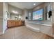 Bathroom featuring a soaking tub under a window with a wide vanity with mirror at 2064 Poetry Ave, Henderson, NV 89052