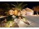 Stunning home exterior at night with landscaped front yard, mature palm trees, and a three car garage at 2064 Poetry Ave, Henderson, NV 89052