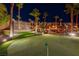 The home features an expansive putting green surrounded by illuminated palm trees, perfect for evening practice at 2064 Poetry Ave, Henderson, NV 89052