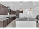 Kitchen with stainless steel appliances, granite counters, dark cabinets, island with sink, and decorative lighting at 2430 Bellinzona Pl, Henderson, NV 89044