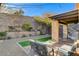 Relaxing backyard featuring a covered patio, desert landscaping, and lush artificial turf at 889 Ariel Heights Ave, Las Vegas, NV 89138