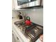 Close-up of the kitchen showcasing a stainless steel gas range, modern backsplash, and white countertops at 889 Ariel Heights Ave, Las Vegas, NV 89138