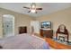 Spacious main bedroom featuring wood floors, a ceiling fan, ensuite bathroom, and a large TV at 3740 Corte Bella Hills Ave, North Las Vegas, NV 89081