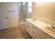 Bathroom featuring a double vanity with marble countertop, tiled shower with glass door, and wood-look flooring at 5841 Genoa Ave, Pahrump, NV 89060