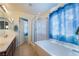 Clean and modern bathroom features a bathtub, glass enclosed shower, and double sink vanity at 7481 Benlomond Ave, Las Vegas, NV 89179