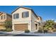 Two-story house with tan exterior, two-car garage, and landscaping at 10548 Seasonable Dr, Las Vegas, NV 89129