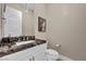 Stylish powder room with dark granite countertop and white cabinets at 10896 Tranquil Hills Way, Las Vegas, NV 89135