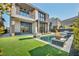 Contemporary home with a modern water feature, a well-manicured lawn, and mature trees at 10896 Tranquil Hills Way, Las Vegas, NV 89135