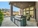 Outdoor kitchen featuring a built-in grill, marble countertop, and view of the modern backyard patio at 10896 Tranquil Hills Way, Las Vegas, NV 89135