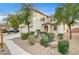 Two-story house with beige exterior, three-car garage, and landscaping at 221 Raptors View Ave, North Las Vegas, NV 89031