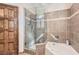 Tiled bathroom showcases glass enclosed shower with tub, wood door, and detailed tile work at 24 Wild Dunes Ct, Las Vegas, NV 89113