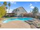 Large kidney shaped pool with surrounding patio and rock waterfall feature at 2619 Grey Stone Rd, Henderson, NV 89074