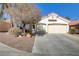 House exterior featuring a two-car garage and mature trees at 4176 Demoline Cir, Las Vegas, NV 89141