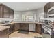 Modern kitchen featuring dark cabinetry, stainless steel appliances, granite countertops, and natural light from the windows at 4330 Flandes St, Las Vegas, NV 89121