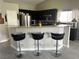 Kitchen breakfast bar area with modern stainless steel appliances, dark cabinetry, and wood-look flooring at 4618 Zia Ridge St, North Las Vegas, NV 89031