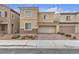 Two-story home featuring tan stucco siding, stone accents, paved driveway, and an attached two-car garage at 5233 Fiery Sky Ridge St, Las Vegas, NV 89148