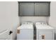 Functional laundry room featuring a side-by-side washer and dryer, gray cabinets, and a clean, organized space at 66 Ibiza Lake Dr, Henderson, NV 89011