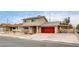 Beige two-story house with red garage door and covered carport at 7232 Raincloud Dr, Las Vegas, NV 89145