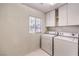 Convenient laundry room featuring a washer, dryer, white cabinets and a window at 86 Myrtle Beach Dr, Henderson, NV 89074