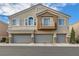 Tan two-story home with gray garage doors and balcony at 8658 Tom Noon Ave # 103, Las Vegas, NV 89178