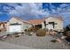 Tan stucco house with tile roof, two-car garage, and desert landscaping at 9900 Rosamond Dr, Las Vegas, NV 89134