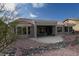 Rear view of the home showcasing the covered patio, landscaping, and rock accents at 9900 Rosamond Dr, Las Vegas, NV 89134