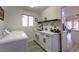 Bright laundry room with white cabinets, quartz countertops, and a utility sink at 9900 Rosamond Dr, Las Vegas, NV 89134