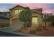 Two-story house with beige exterior, landscaping, and a two-car garage at dusk at 10260 Danskin Dr, Las Vegas, NV 89166