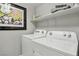 Bright laundry room featuring a Whirlpool washer and dryer, complemented by a shelf for storage and cheerful artwork at 104 Alamere Falls Dr, Las Vegas, NV 89138