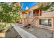 Exterior side view of a two-story condo with lush landscaping, a courtyard, and walkway to main entrance at 1600 N Torrey Pines Dr # 202, Las Vegas, NV 89108