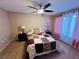 A comfy bedroom features a ceiling fan and soft pink curtains providing light control and adding to the cozy feel at 5710 E Tropicana Ave # 2122, Las Vegas, NV 89122