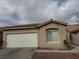 Tan house with a white garage door and a landscaped yard at 9712 Tiaquinn Ave # 101, Las Vegas, NV 89129