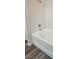 Corner view of a clean white bathtub with tile walls and new gray laminate flooring at 10337 Adams Chase St, Las Vegas, NV 89183
