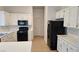 Spacious kitchen featuring white cabinetry, black appliances, and a tiled floor, perfect for culinary adventures at 10337 Adams Chase St, Las Vegas, NV 89183