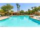 Community pool with rock features, tall trees, and a covered seating area at 11870 Tevare Ln # 2086, Las Vegas, NV 89138