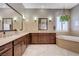 Luxurious bathroom featuring double vanities, a soaking tub, tile flooring, and bright lighting at 2425 Amatrice St, Henderson, NV 89044