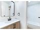 Stylish bathroom with a wooden vanity, black fixtures, and a white tiled bathtub/shower, offering a modern and sleek design at 3339 Duece St, Las Vegas, NV 89121