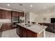 A well-lit kitchen featuring stainless steel appliances, granite countertops, brown cabinetry and a kitchen island with sink and barstool seating at 365 Andy Wheeler Dr, Henderson, NV 89011