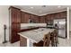 A spacious kitchen with brown cabinets, granite counters, stainless appliances, and a large kitchen island with bar stool seating at 365 Andy Wheeler Dr, Henderson, NV 89011