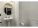 This is a half-bathroom with a pedestal sink, toilet, and mirror at 365 Andy Wheeler Dr, Henderson, NV 89011