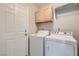 A well-organized laundry area with white appliances, upper cabinets for storage, and a door for privacy and convenience at 412 Lost Trail Dr, Henderson, NV 89014