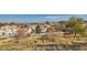 Elevated view of a neighborhood showcasing red-tiled roofs, lush trees, and a glimpse of the city skyline in the distance at 412 Lost Trail Dr, Henderson, NV 89014