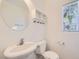Well-lit half bathroom featuring a pedestal sink, toilet, mirror and storage shelves at 9140 Silk Threads Ave, Las Vegas, NV 89149