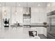 Modern white kitchen with stainless steel appliances, island with bar seating, and pendant lighting at 9145 Las Manaitas Ave # 401, Las Vegas, NV 89144