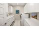 Clean laundry room features white cabinets and appliances, sleek fixtures, and modern artwork at 9145 Las Manaitas Ave # 401, Las Vegas, NV 89144