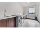 Bright laundry room with modern washer and dryer and wooden cabinets at 1341 Villa Barolo Ave, Henderson, NV 89052
