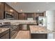 Modern kitchen with stainless steel appliances, granite countertops, and dark wood cabinets at 374 Yellow Finch Ln, Henderson, NV 89012