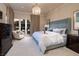 A chandelier hangs over this main bedroom with neutral colors, outdoor access and dark wood dressers at 641 Saint Croix St, Henderson, NV 89012