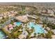 Aerial view of a community clubhouse with a sprawling pool, palm trees, and ample parking at 664 Orchard Course Dr, Las Vegas, NV 89148